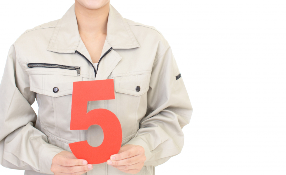 数字の５を持つ作業服の女性