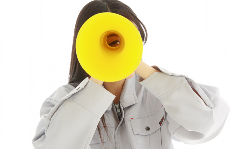 黄色いメガホンを覗く作業服の女性